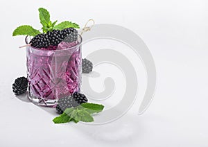 Glass of refreshing summer cocktail with blackberry, ice and mint on white background. Soda and alcohol mix