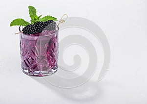 Glass of refreshing summer cocktail with blackberry, ice and mint on white background. Soda and alcohol mix