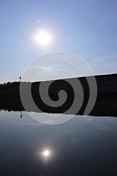 Glass river surface shore hill reflection. Blue sky and water and central beautiful scenic tranquill