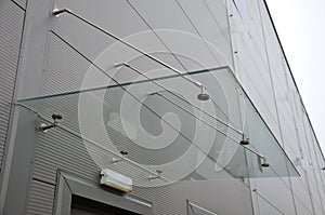 Glass roof above the entrance to the industrial building with metal cladding of the facade. thick-walled glass panel hangs above t