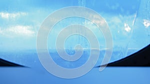 On the glass round porthole of the ship flowing water, splashes from the waves. Background blue