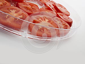 Glass salad bowl filled with raw tomato slices photo
