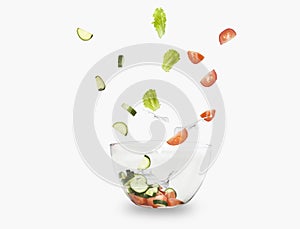 glass salad bowl in flight with vegetables: tomato, cucumber and leaf salad. Isolated on white background. healthy diet.