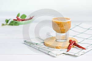 Glass of salad dressing on white table with Kaffir lime and chili ingredient