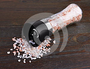 Glass saltcellar with salt on wood photo