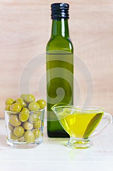 Glass sauceboat with extra virgin olive oilÐ±  fresh green olives and bottle on wooden table