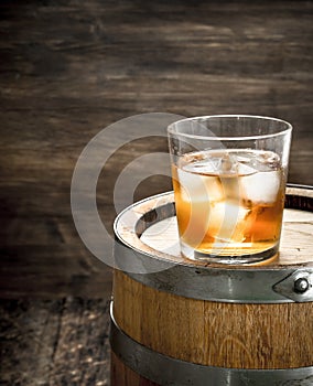 glass of Scotch whiskey with a barrel.