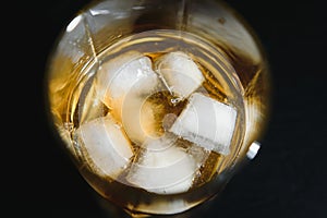 Glass of scotch whiskey and ice over black background