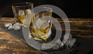 Glass of scotch whiskey and ice on wooden table