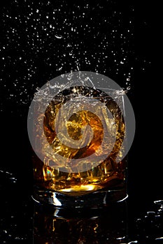 glass of scotch whiskey with splash and ice