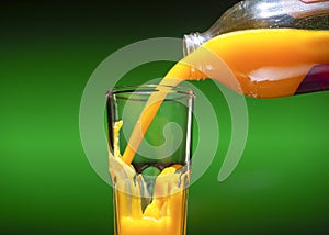 Glass with sea buckthorn juice and a bottle isolated on green background