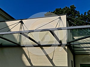 glass shelter by a beige historical building. attached to the facade of the wall