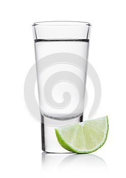 Glass shot of silver tequila with lime slice on white photo