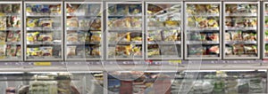Glass showcase with frozen foods in a large light supermarket. Blurred. Panorama format. Front view