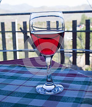 A glass of Sicilian red wine on the table covered with checkered tablecloth