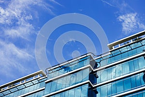 Glass skyscraper building with cloudy blue sky background