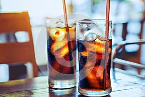 Glass of softdrink splashing with fresh ice on wooden table back