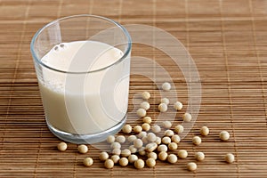 Glass of soya milk with froth on bamboo mat with spilled soya be