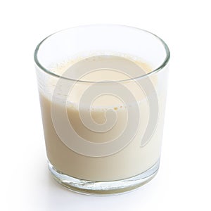 Glass of soya milk with froth on white.