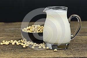A glass of soymilk with soybeans on wooden table background