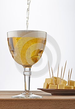 Glass of sparkling Belgian beer with cheese on white