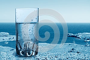 Glass of sparkling pure water against the sea background