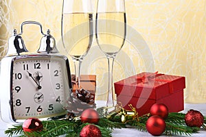 Glass of sparkling shampagne wine, clock, gift box and candles on christmas background.