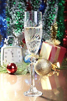 Glass of sparkling shampagne wine Clock and gift box on christmas background