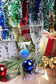 Glass of sparkling shampagne wine clock and gift box on christmas background