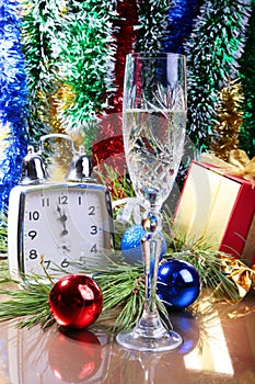 Glass of sparkling shampagne wine clock and gift box on christmas background