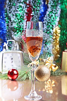 Glass of sparkling shampagne wine clock and gift box on christmas background