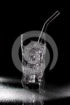 Glass of sparkling water soda drink with ice on black background