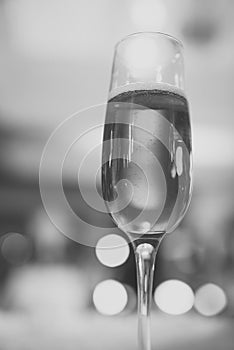 Glass of sparkling wine with bubbles on bokeh background