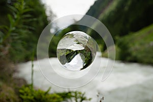 Glass sphere floating over river in the alps