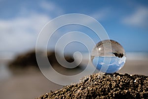Glass sphere lying on the rock of a beach on a sunny