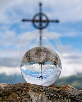 Glass sphere lying on a rock in front of summit cross