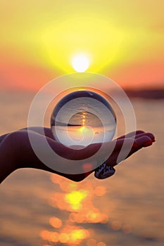Glass sphere in the palm with an inverted reflection of the sunset on the sea in Turkey in Kizilagac photo