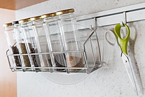 Glass spice jars with spices on a hanging metal shelf