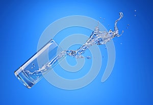 Glass with spilling water splash. Side view. On blue background