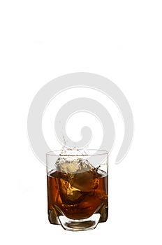 Glass with splash of whisky with ice cube