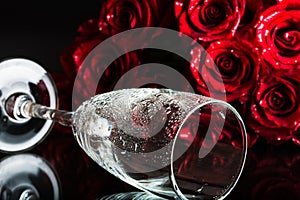 A glass with splashes of water and a bouquet of roses. The atmosphere of romance