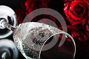 A glass with splashes of water and a bouquet of roses. The atmosphere of romance