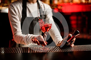 glass with splashing cocktail decorated with flower on bar counter