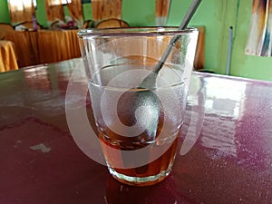 a glass with a spoon in it and the remaining tea water