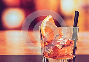 Glass of spritz aperitif aperol cocktail with orange slices and ice cubes on bar table, vintage atmosphere background