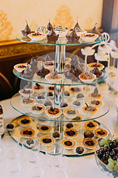 The glass stand covered with differen wedding cupcakes.