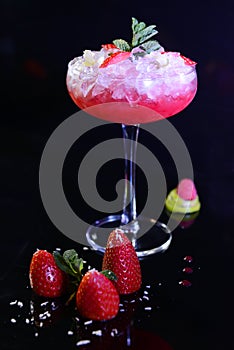 Glass of strawberry juice with ice cubes and strawberries on a table photo
