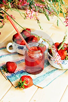 A glass of strawberry smoothie on a wooden background. Strawberr
