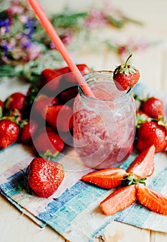 A glass of strawberry smoothie on a wooden background. Strawberr