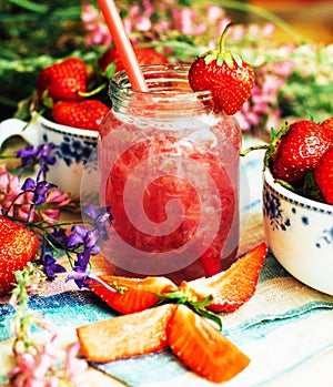 A glass of strawberry smoothie on a wooden background. Strawberr